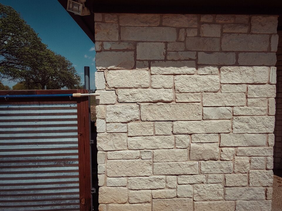 Stair-step crack climbing limestone veneer at a house corner in Central Texas