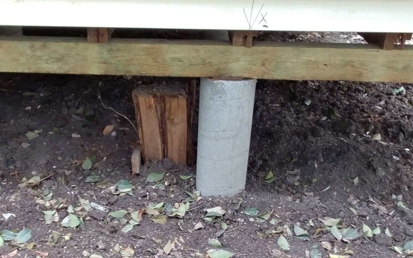 Pier and shim stack supporting a wood beam in a Waco crawl space