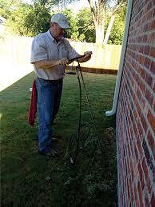 Technician injecting StableSoil along the brick perimeter of an existing home