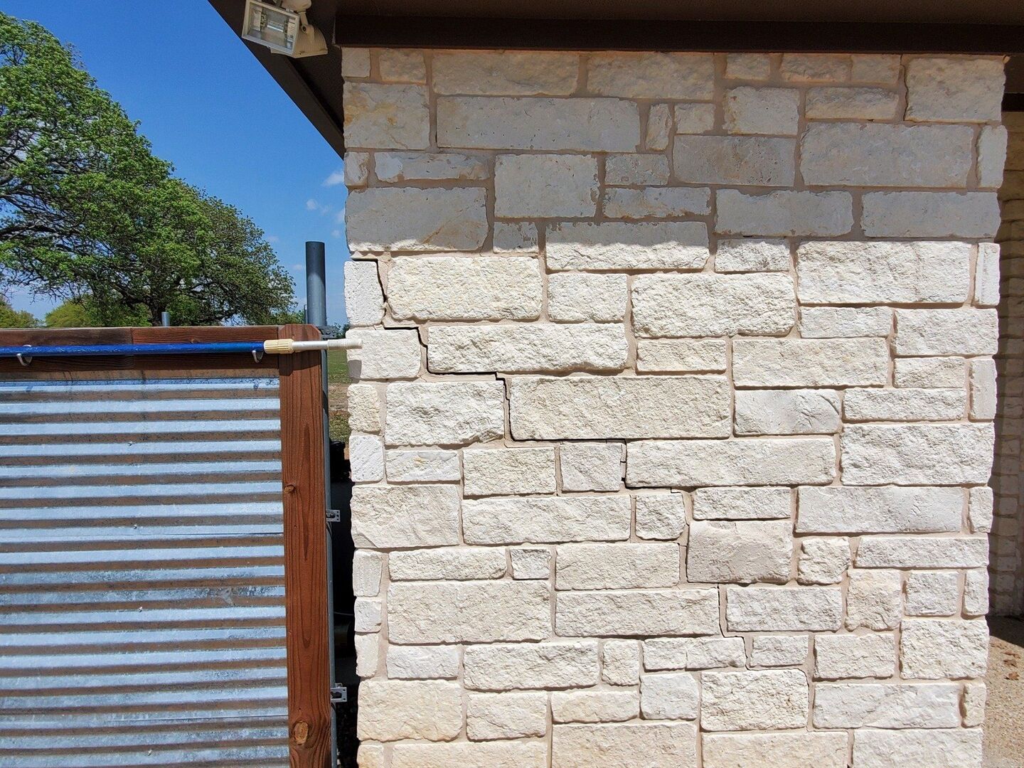 Stair-step crack in limestone veneer at a Central Texas home corner
